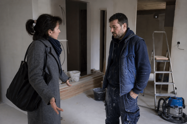 Deux personnes discutent des travaux dans une pièce en rénovation