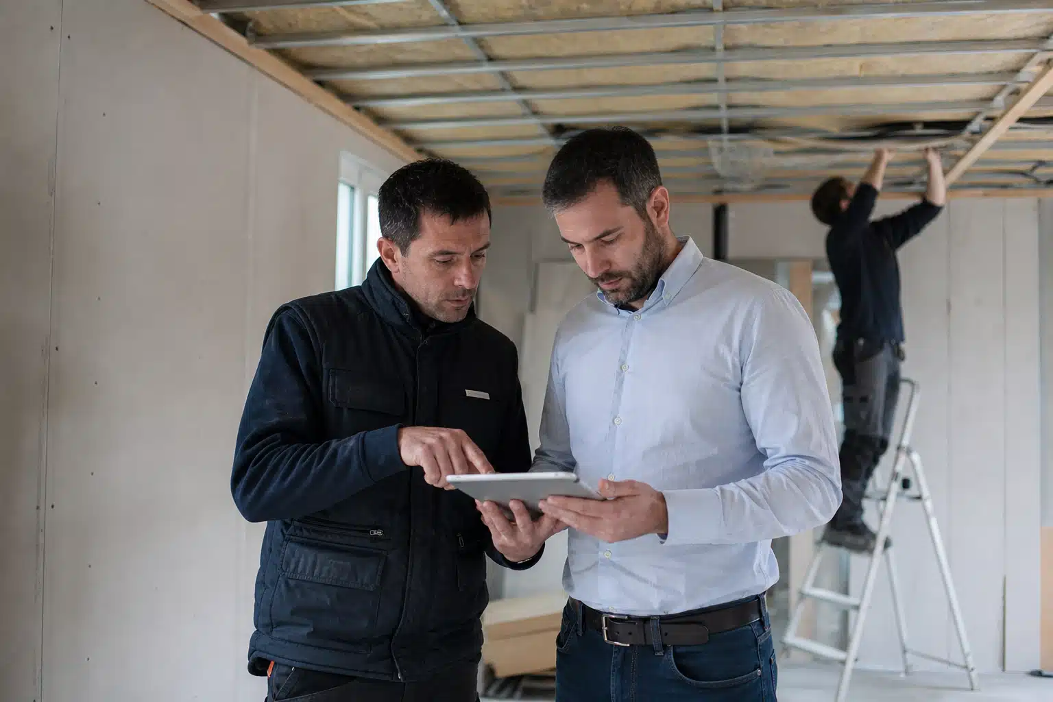 Deux hommes consultant une tablette sur un chantier