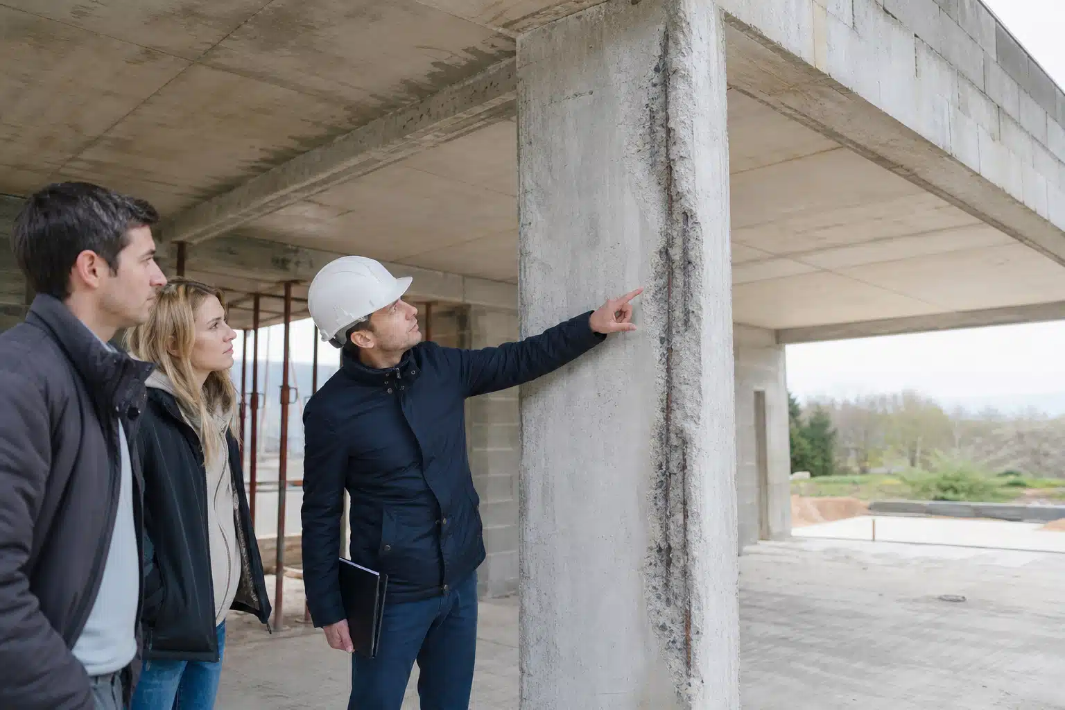 Homme en casque montrant une colonne en béton