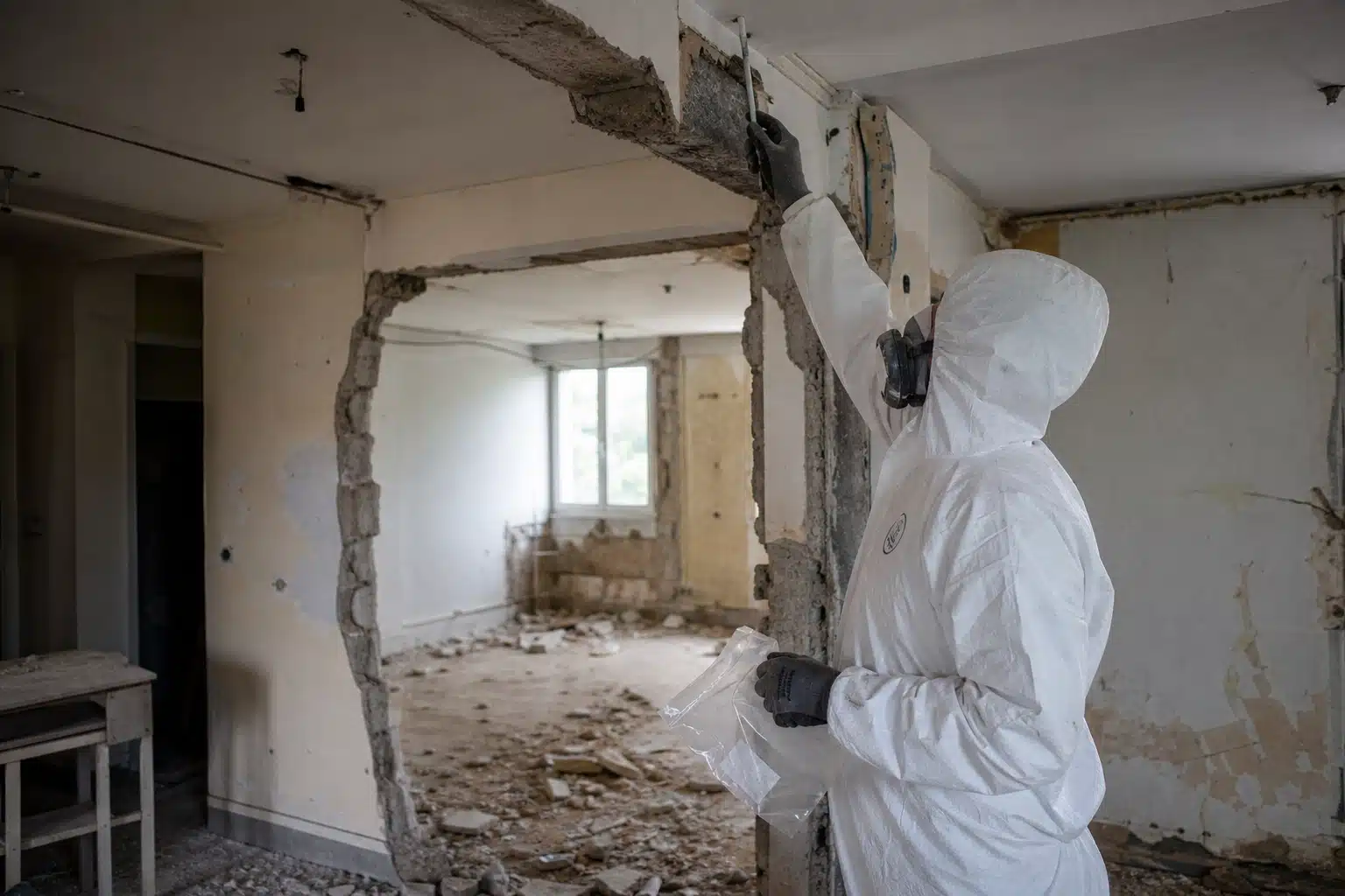 Technicien en combinaison inspectant intérieur partiellement démoli